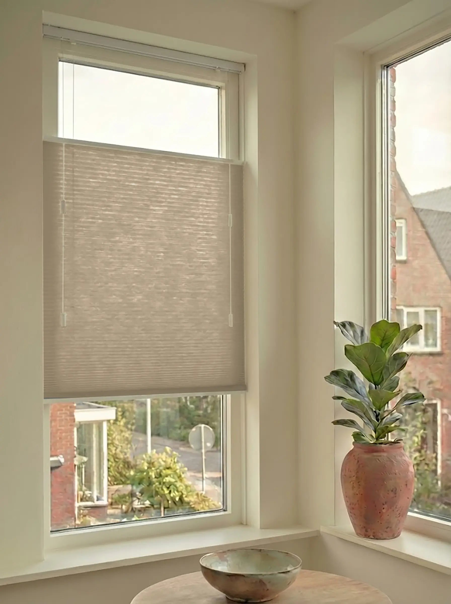 Lichtdoorlatend plisségordijn in Top Down Bottom Up uitvoering, gemonteerd in een licht interieur bij een raam met uitzicht.