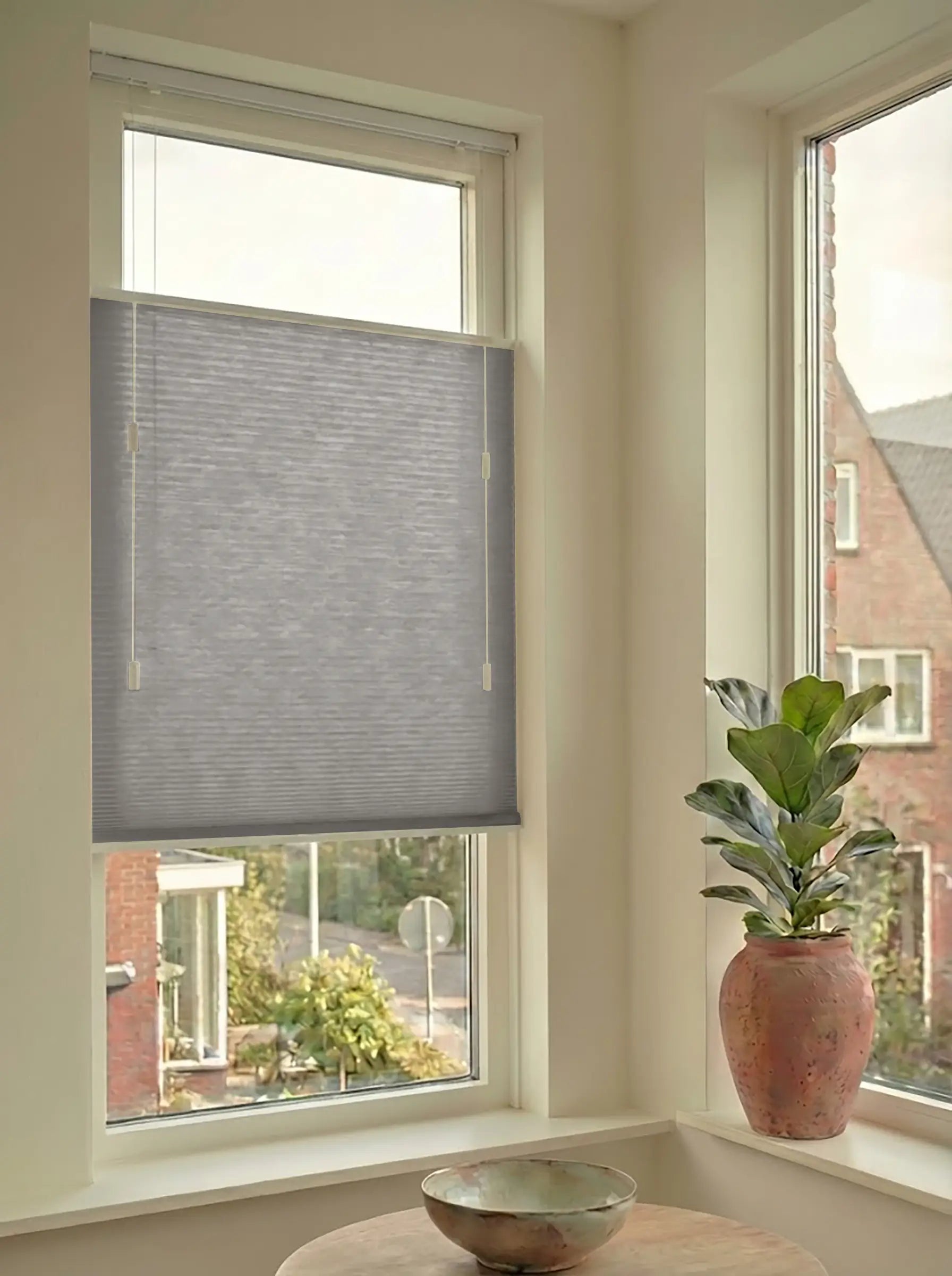 Lichtdoorlatend plisségordijn in Top Down Bottom Up uitvoering, gemonteerd in een licht interieur bij een raam met uitzicht.