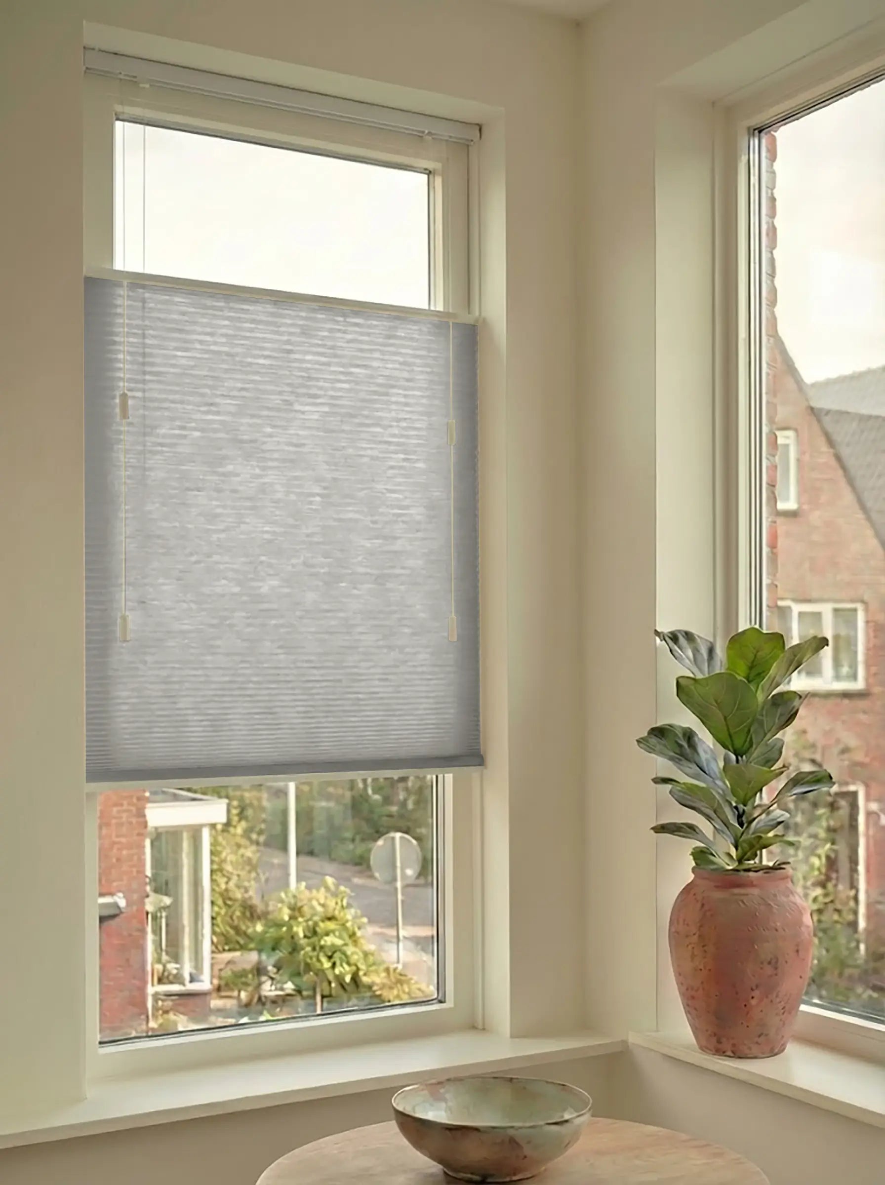 Lichtdoorlatend plisségordijn in Top Down Bottom Up uitvoering, gemonteerd in een licht interieur bij een raam met uitzicht.