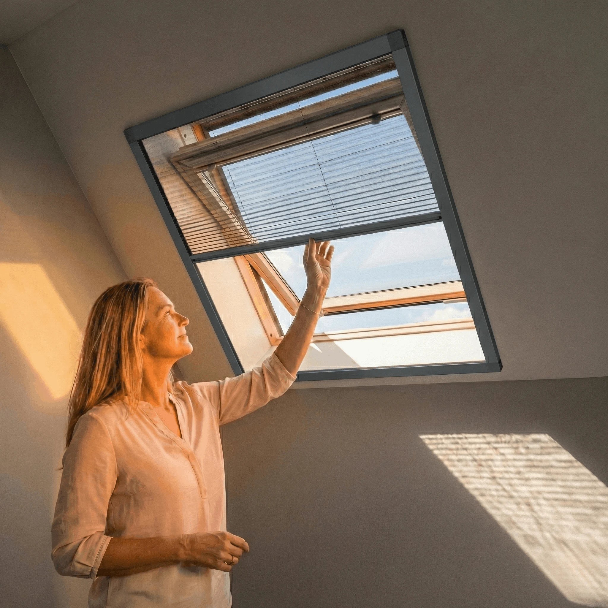 Plissé dakraamhor in antraciet frame gemonteerd op een geopend dakraam, bediend van onder naar boven voor ventilatie zonder insecten.
