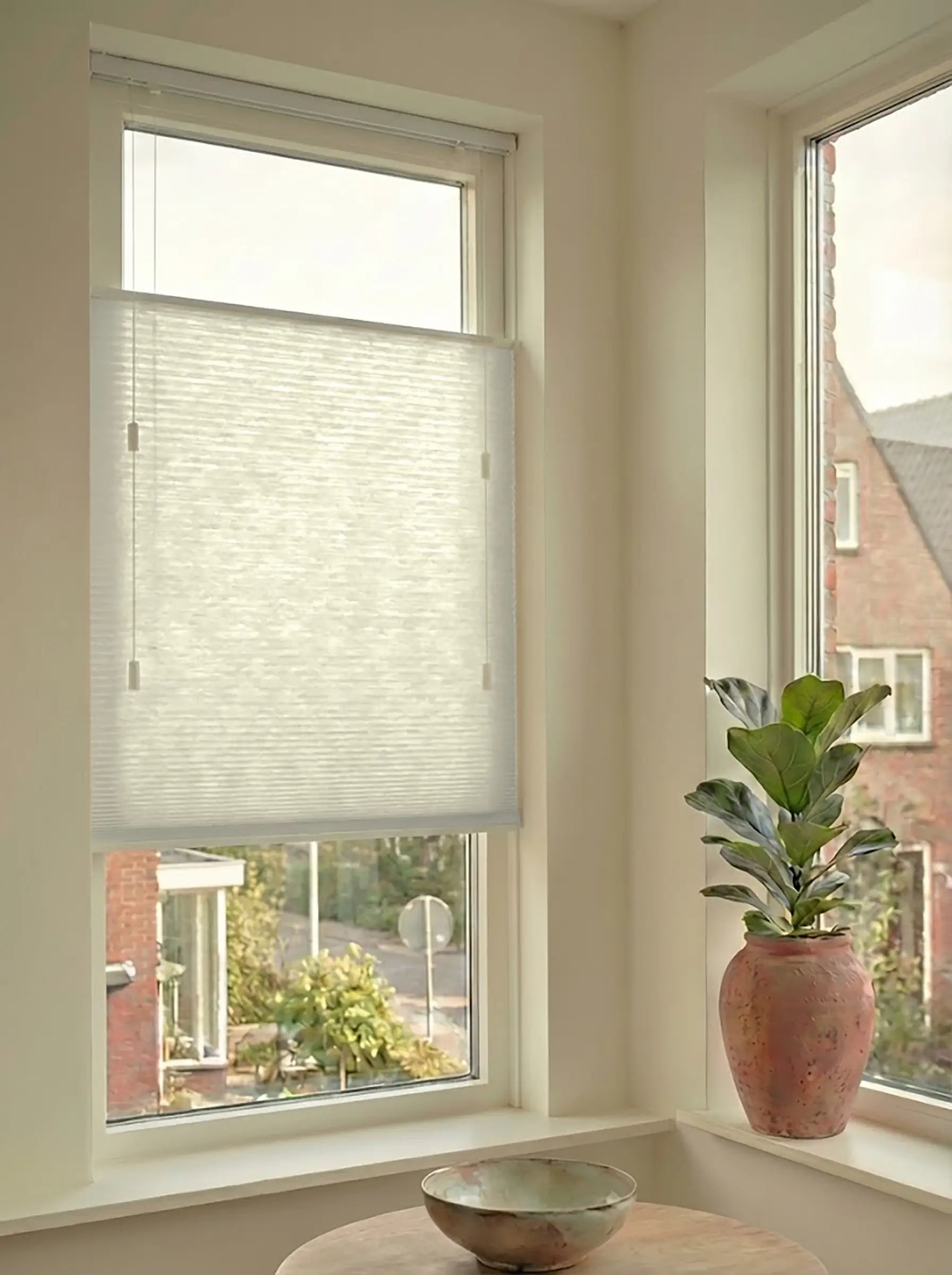 Lichtdoorlatend plisségordijn in Top Down Bottom Up uitvoering, gemonteerd in een licht interieur bij een raam met uitzicht.