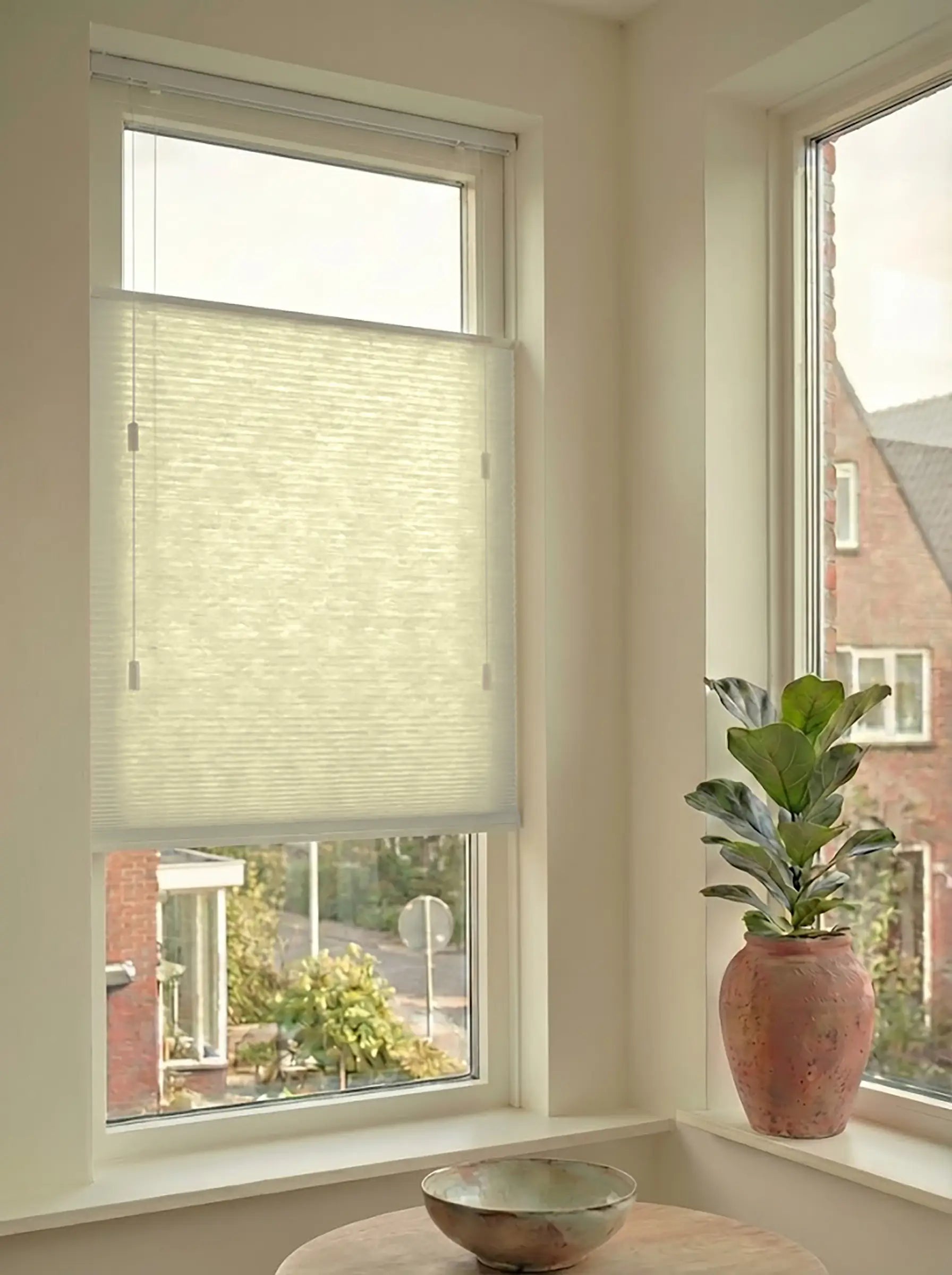Lichtdoorlatend plisségordijn in Top Down Bottom Up uitvoering, gemonteerd in een licht interieur bij een raam met uitzicht.