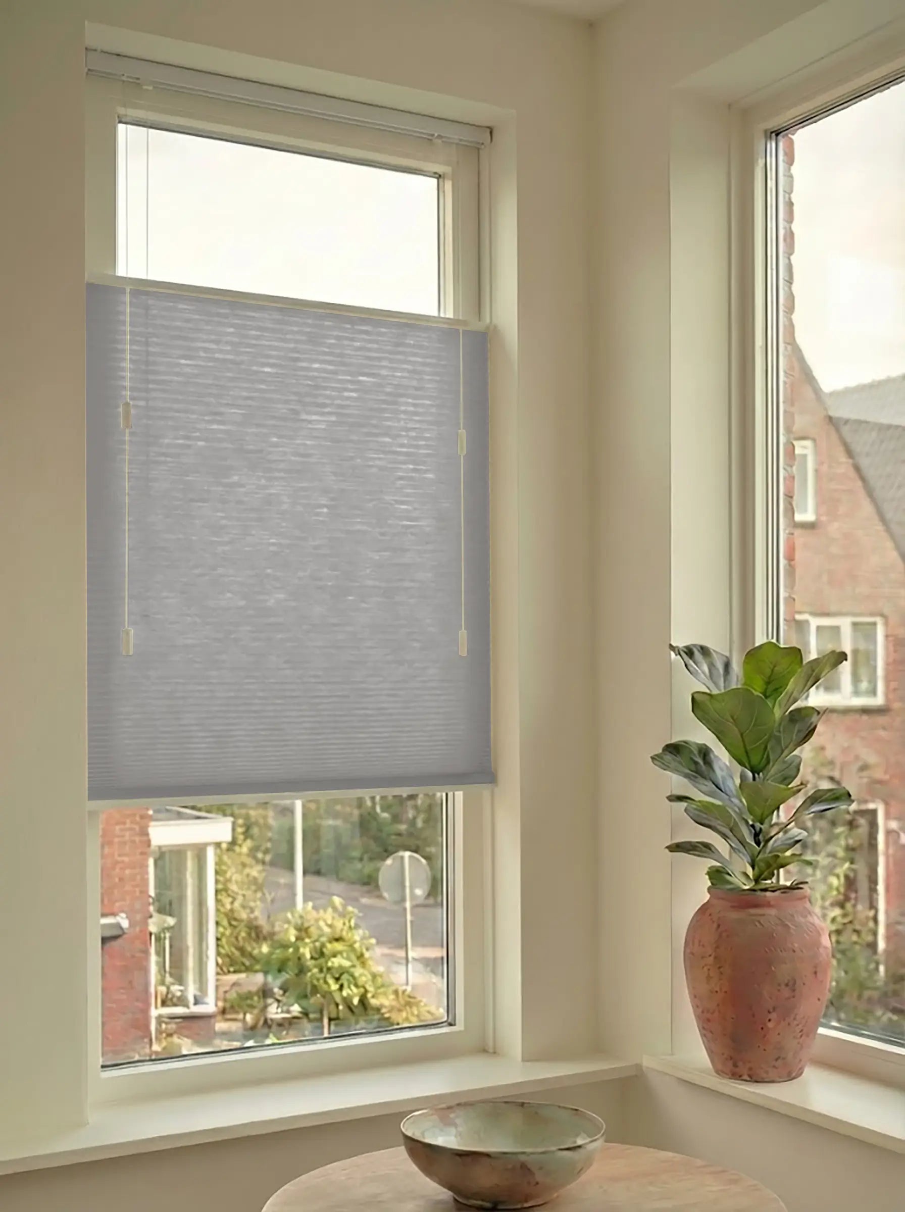 Lichtdoorlatend plisségordijn in Top Down Bottom Up uitvoering, gemonteerd in een licht interieur bij een raam met uitzicht.