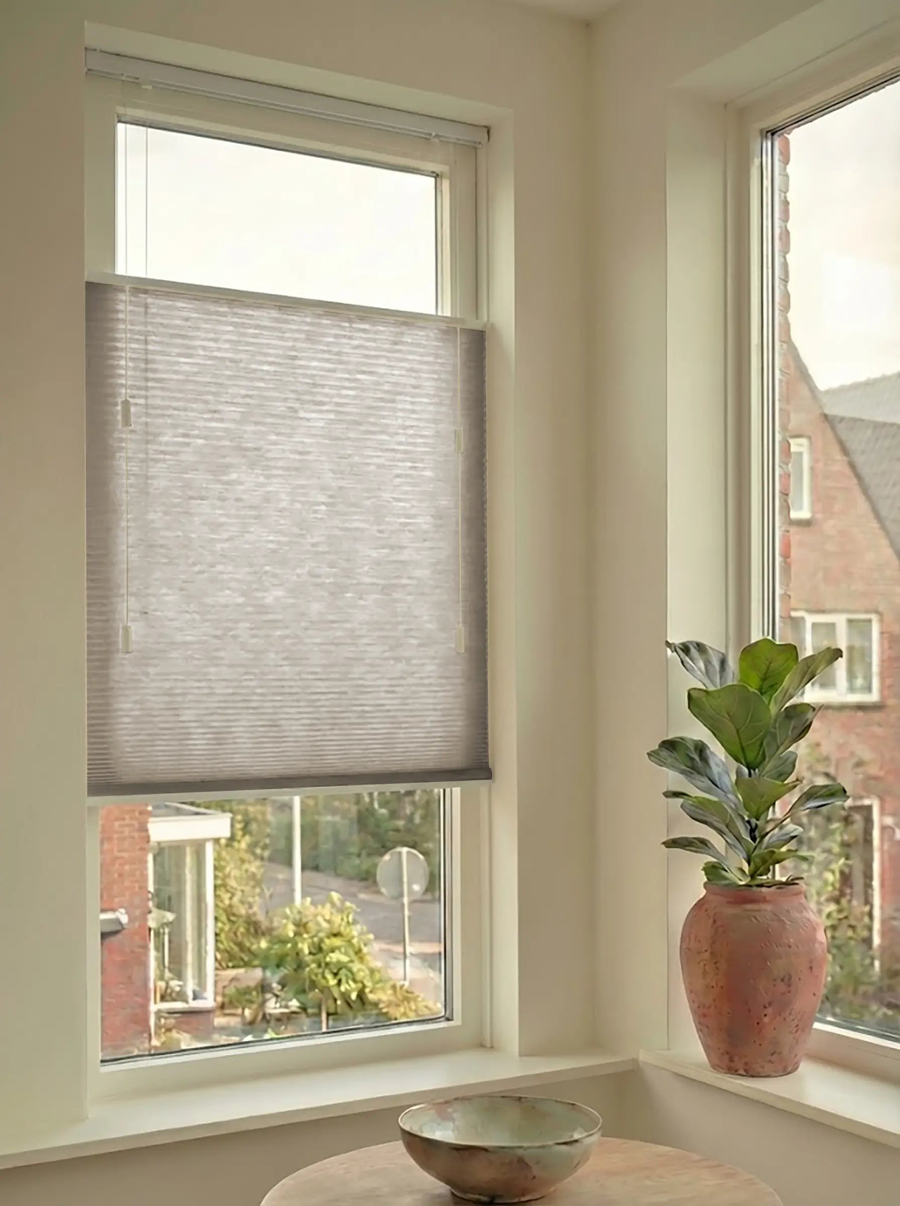 Lichtdoorlatend plisségordijn in Top Down Bottom Up uitvoering, gemonteerd in een licht interieur bij een raam met uitzicht.