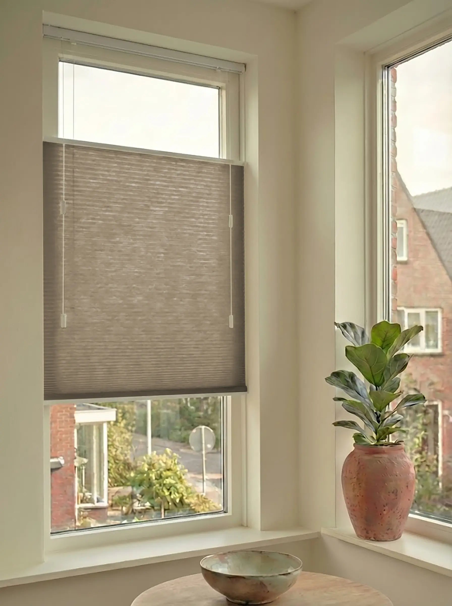 Lichtdoorlatend plisségordijn in Top Down Bottom Up uitvoering, gemonteerd in een licht interieur bij een raam met uitzicht.