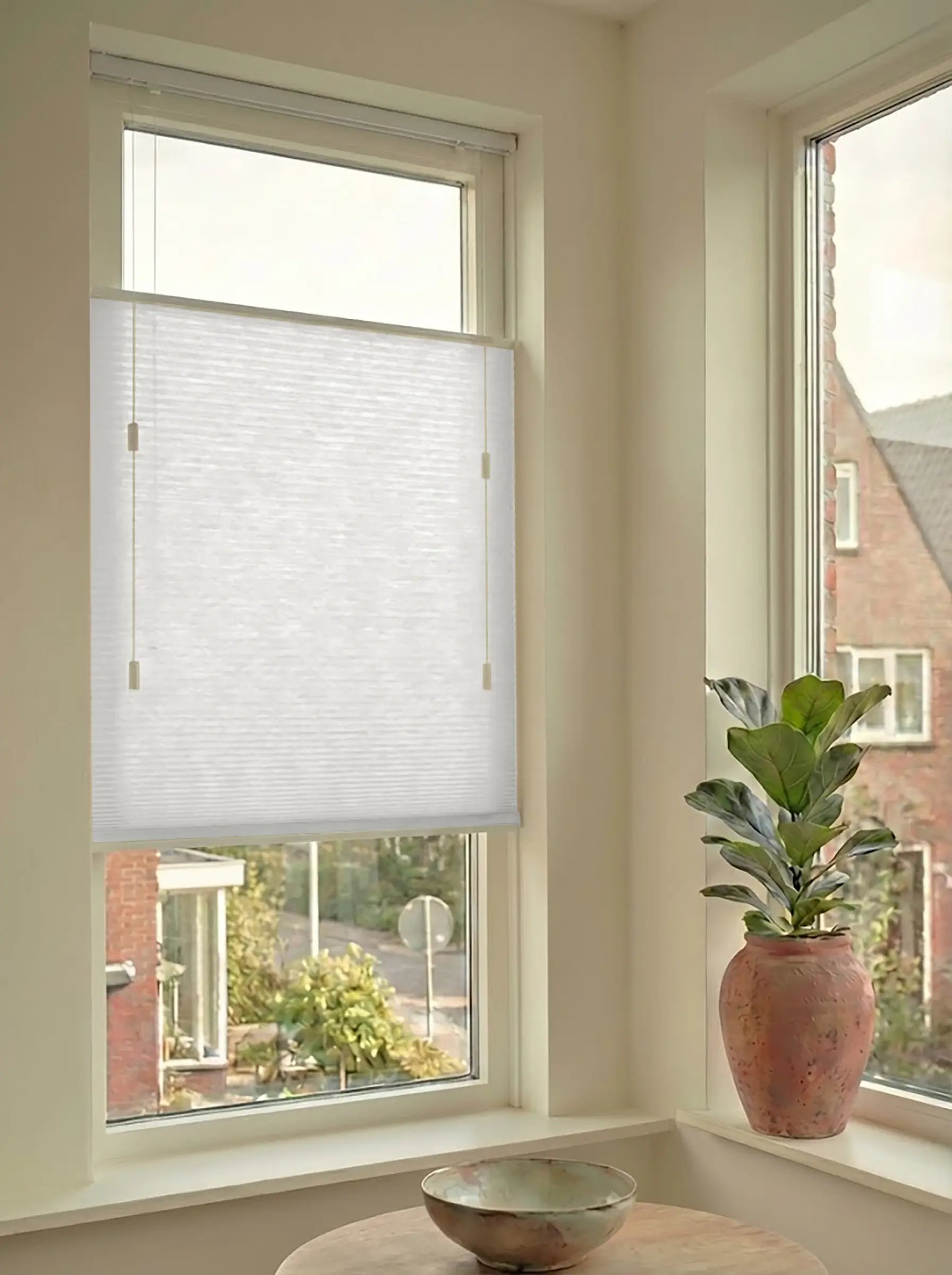 Lichtdoorlatend plisségordijn in Top Down Bottom Up uitvoering, gemonteerd in een licht interieur bij een raam met uitzicht.