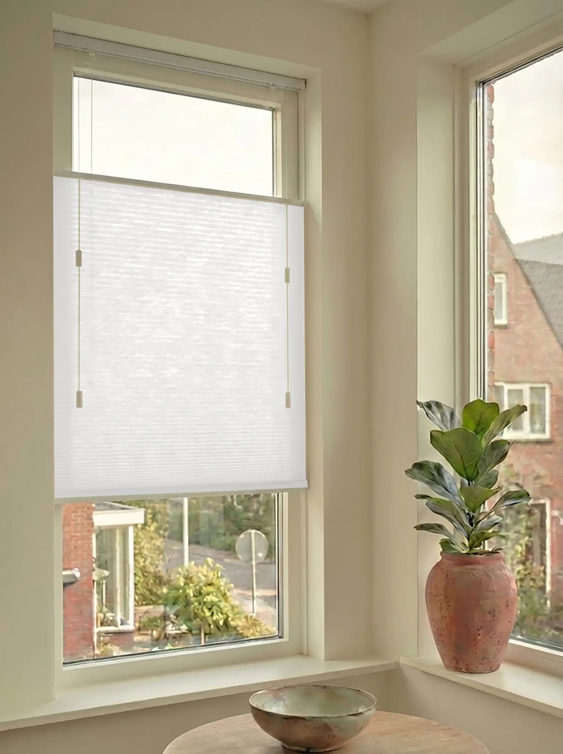 Lichtdoorlatend plisségordijn in Top Down Bottom Up uitvoering, gemonteerd in een licht interieur bij een raam met uitzicht.