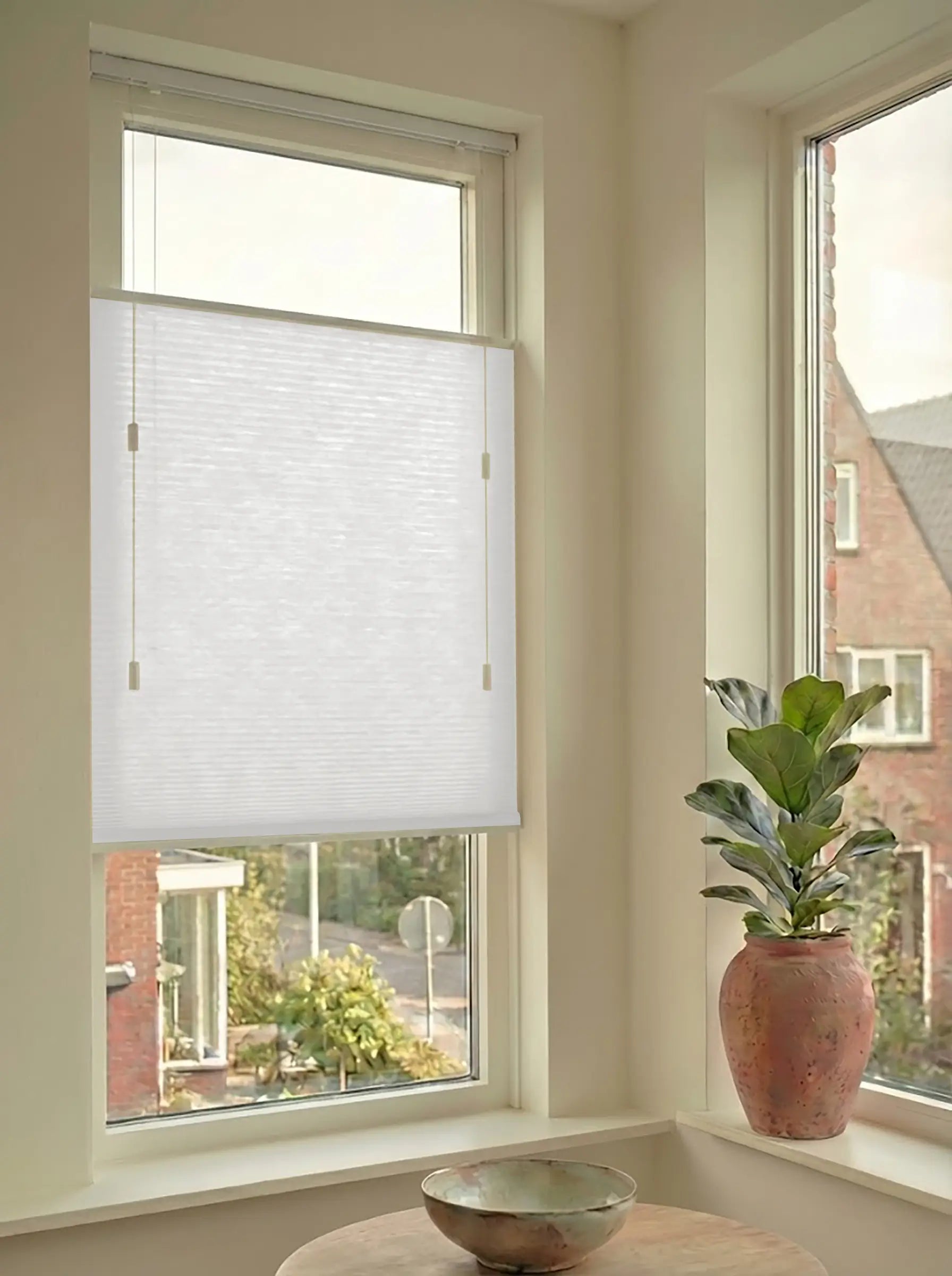 Lichtdoorlatend plisségordijn in Top Down Bottom Up uitvoering, gemonteerd in een licht interieur bij een raam met uitzicht.