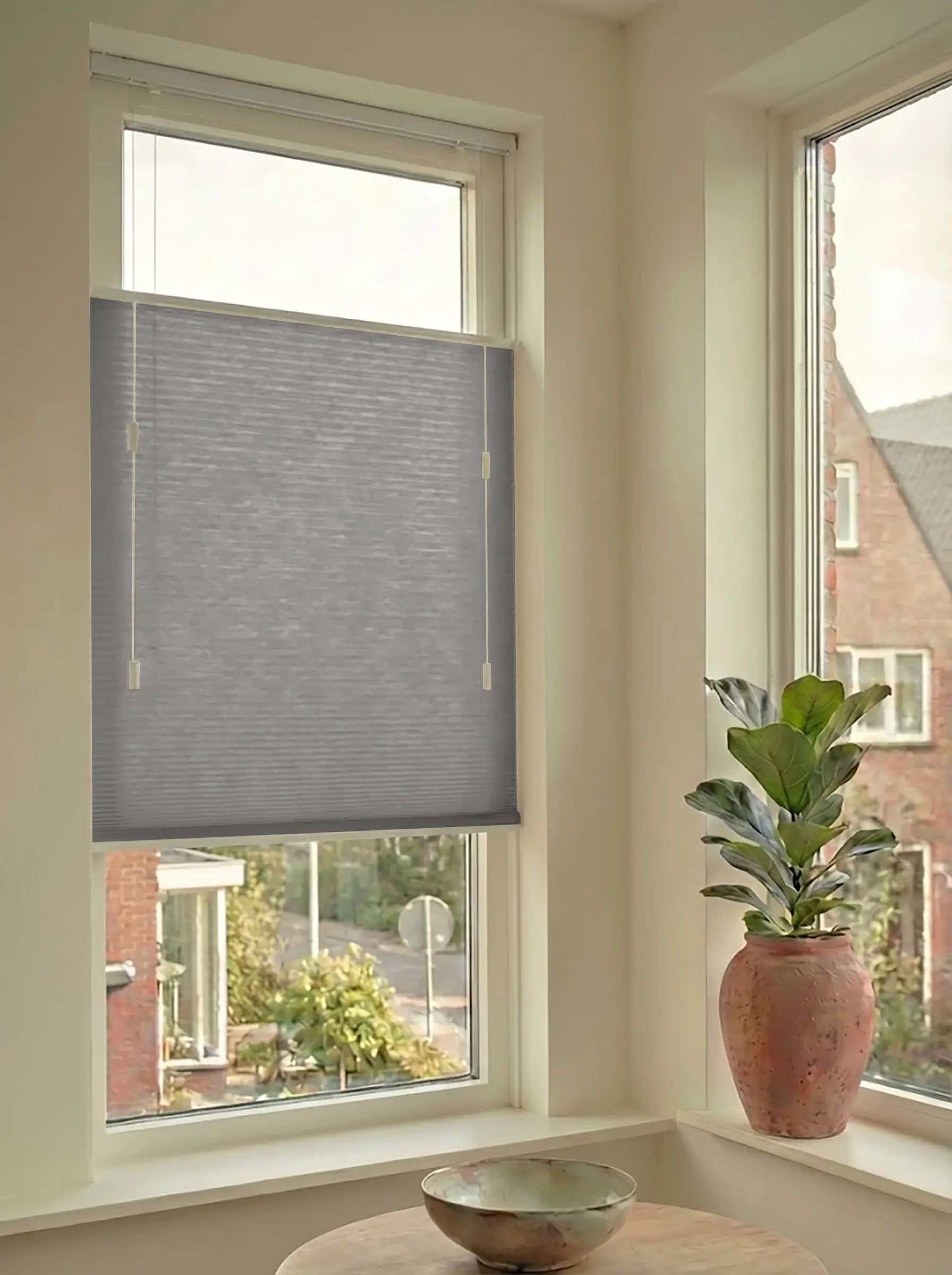 Lichtdoorlatend plisségordijn in Top Down Bottom Up uitvoering, gemonteerd in een licht interieur bij een raam met uitzicht.