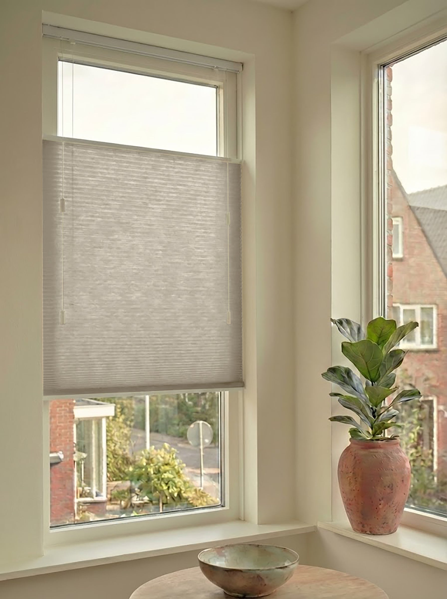 Lichtdoorlatend plisségordijn in Top Down Bottom Up uitvoering, gemonteerd in een licht interieur bij een raam met uitzicht.