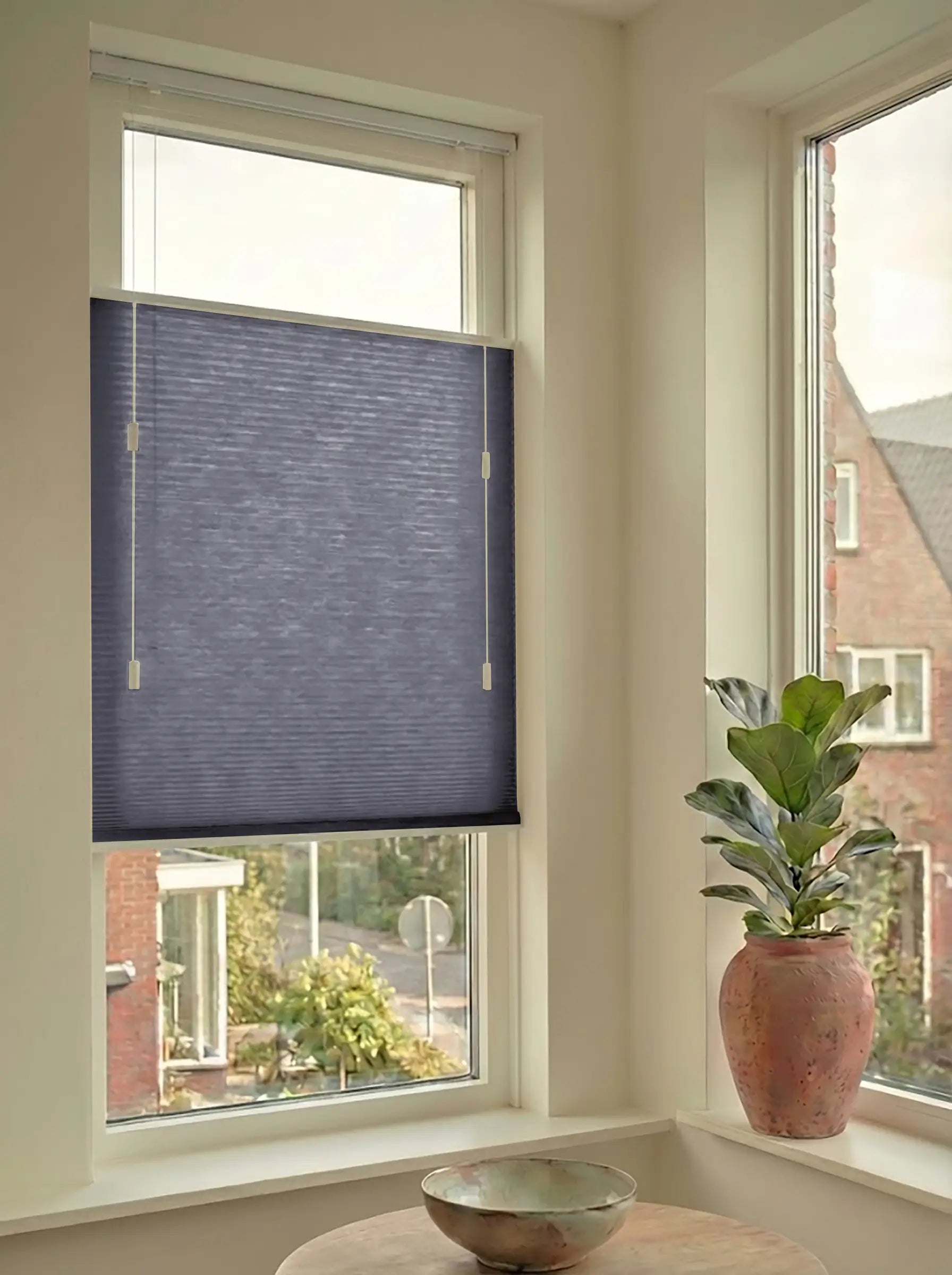 Lichtdoorlatend plisségordijn in Top Down Bottom Up uitvoering, gemonteerd in een licht interieur bij een raam met uitzicht.