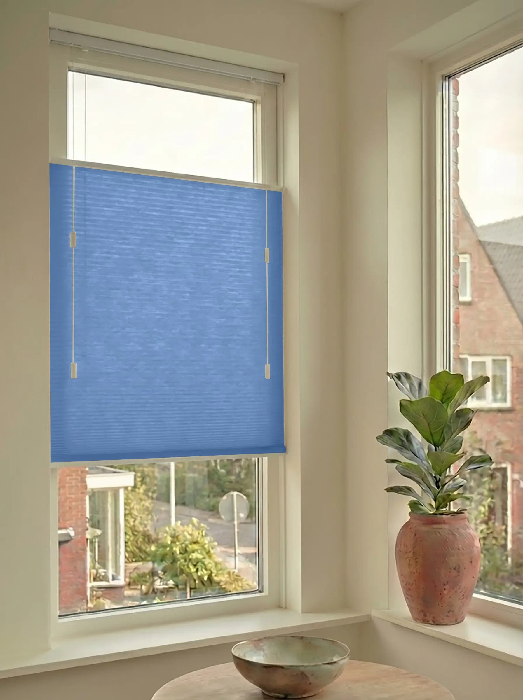 Lichtdoorlatend plisségordijn in Top Down Bottom Up uitvoering, gemonteerd in een licht interieur bij een raam met uitzicht.