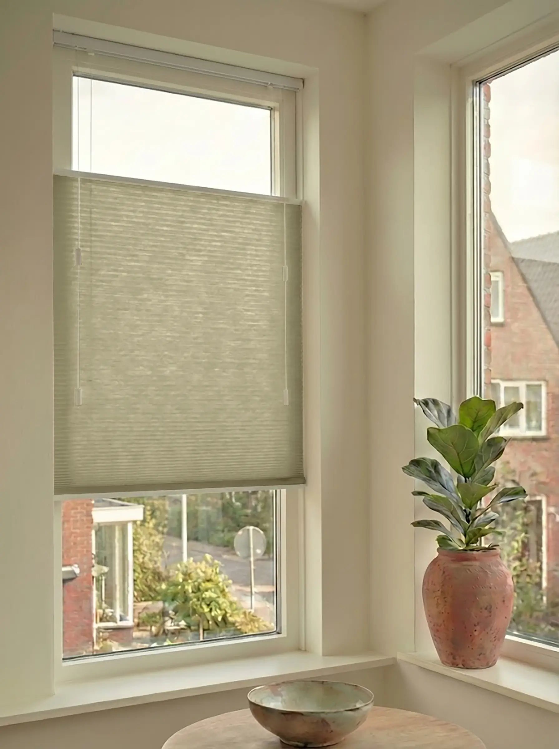 Lichtdoorlatend plisségordijn in Top Down Bottom Up uitvoering, gemonteerd in een licht interieur bij een raam met uitzicht.