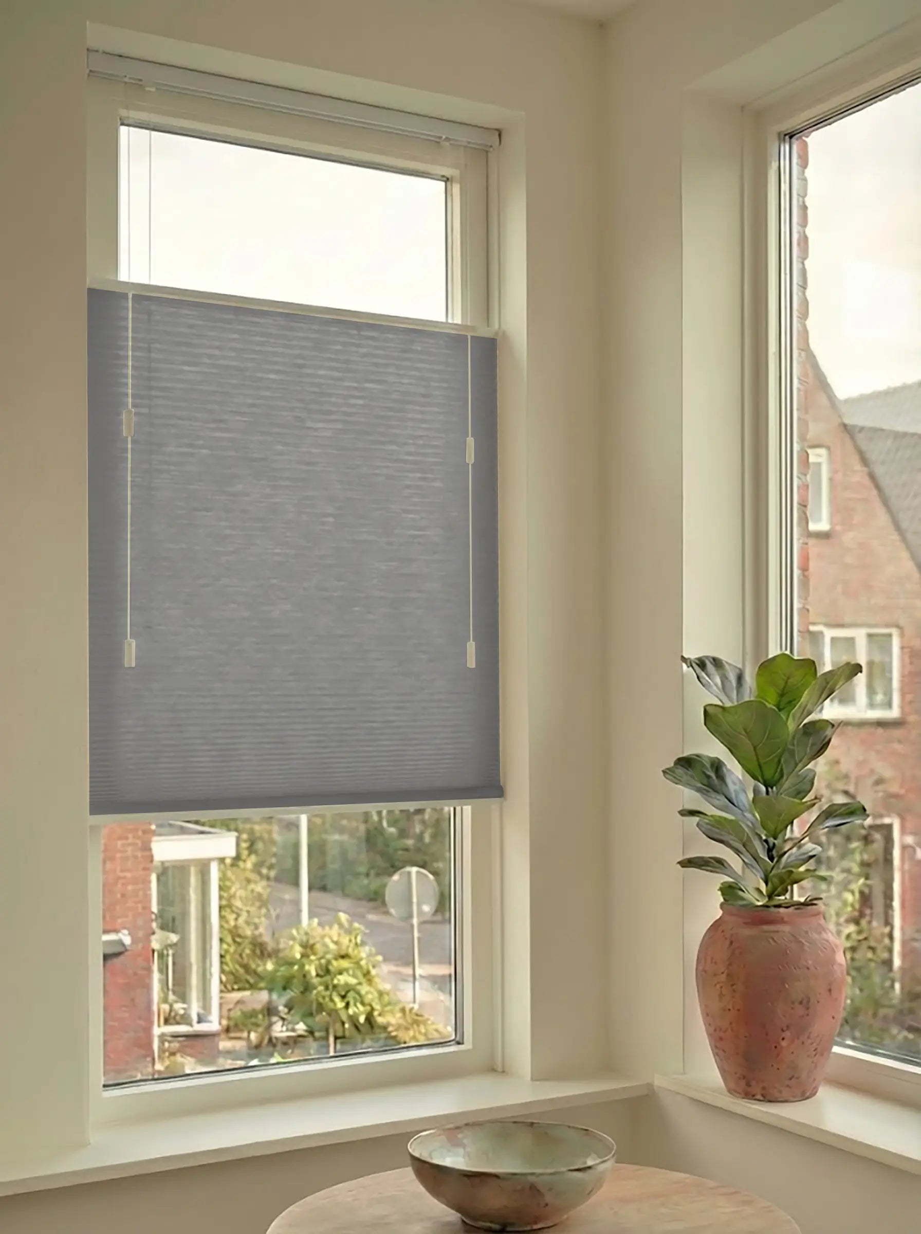 Lichtdoorlatend plisségordijn in Top Down Bottom Up uitvoering, gemonteerd in een licht interieur bij een raam met uitzicht.