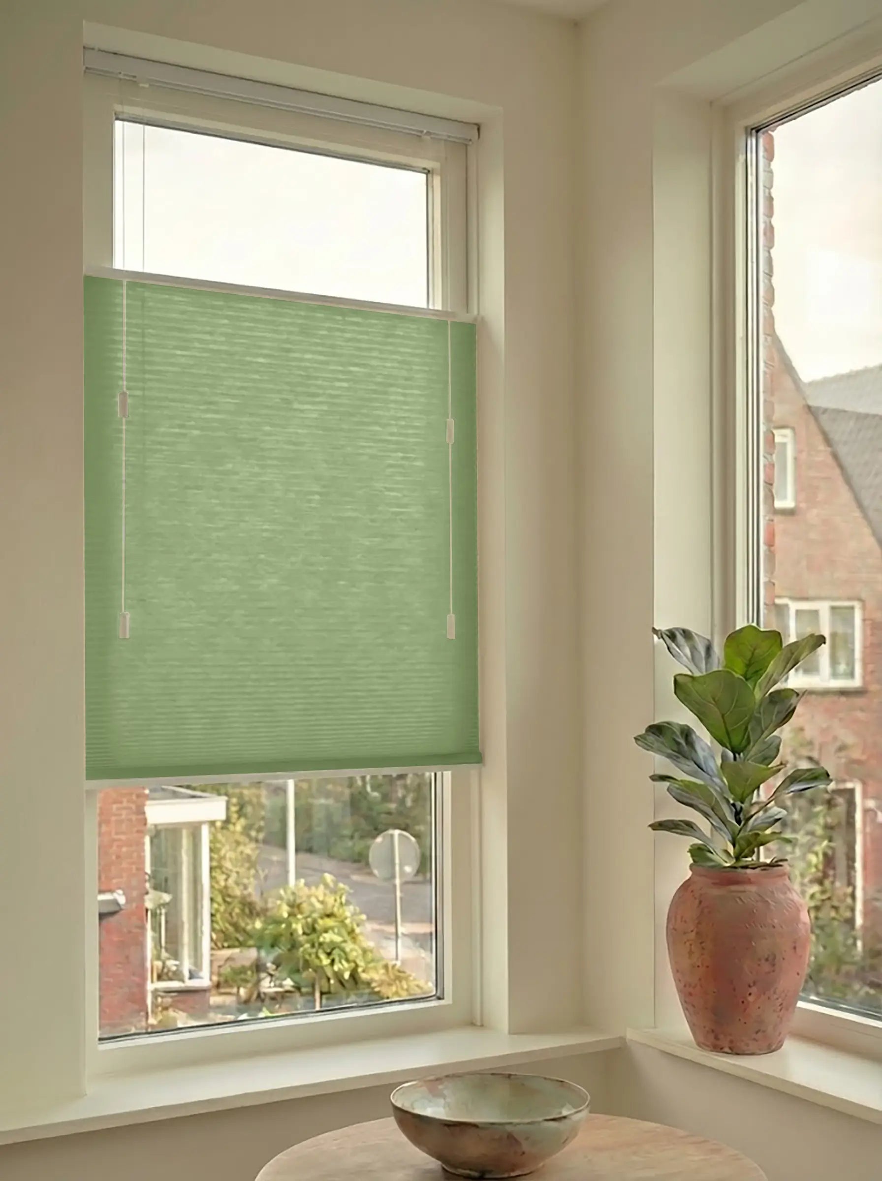 Lichtdoorlatend plisségordijn in Top Down Bottom Up uitvoering, gemonteerd in een licht interieur bij een raam met uitzicht.