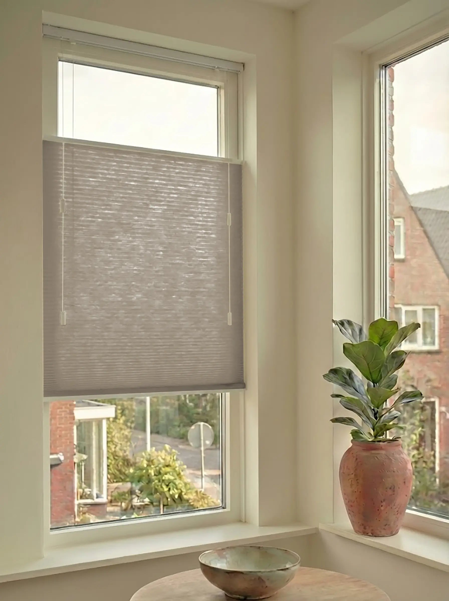 Lichtdoorlatend plisségordijn in Top Down Bottom Up uitvoering, gemonteerd in een licht interieur bij een raam met uitzicht.