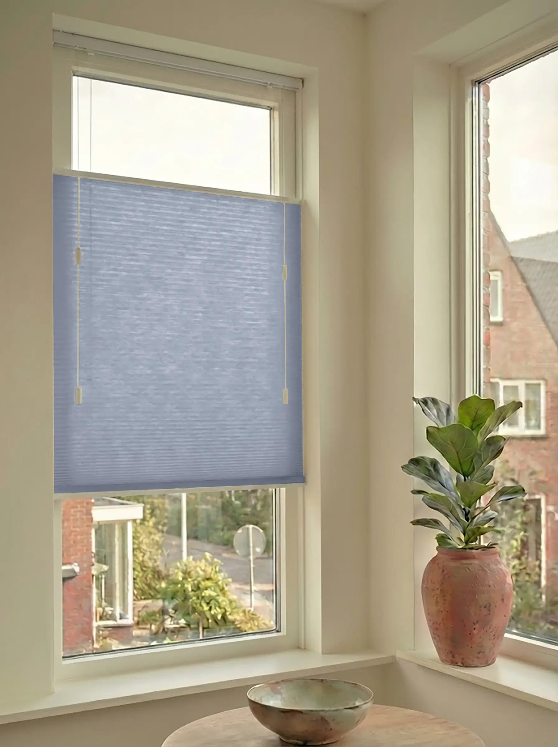 Lichtdoorlatend plisségordijn in Top Down Bottom Up uitvoering, gemonteerd in een licht interieur bij een raam met uitzicht.