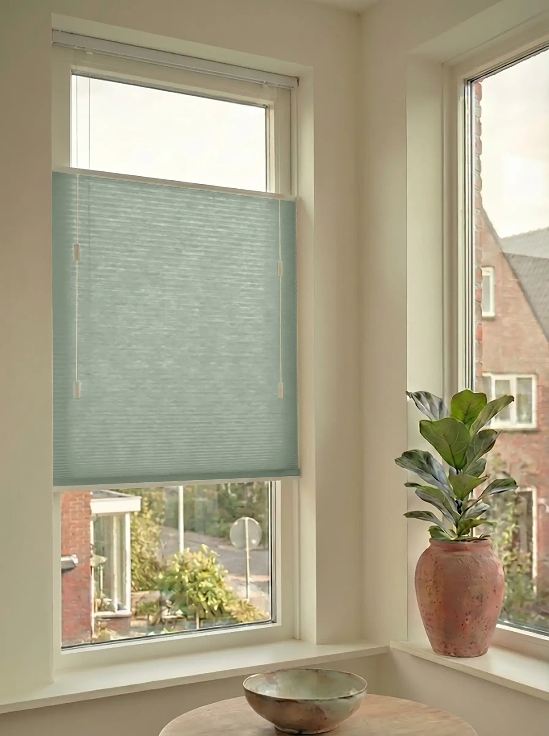 Lichtdoorlatend plisségordijn in Top Down Bottom Up uitvoering, gemonteerd in een licht interieur bij een raam met uitzicht.