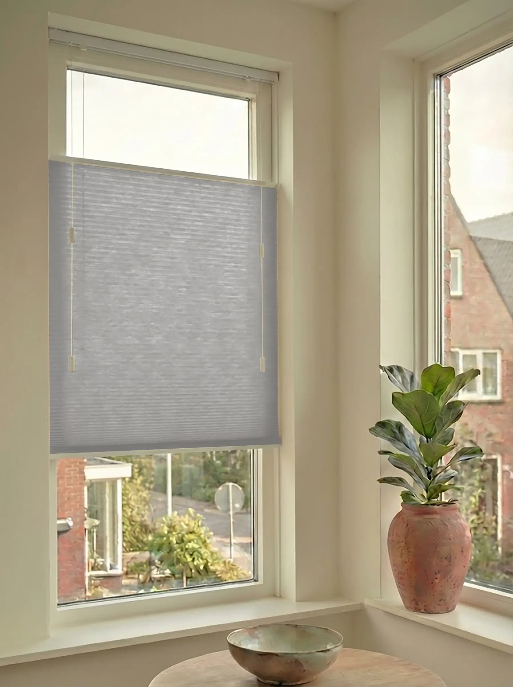 Lichtdoorlatend plisségordijn in Top Down Bottom Up uitvoering, gemonteerd in een licht interieur bij een raam met uitzicht.