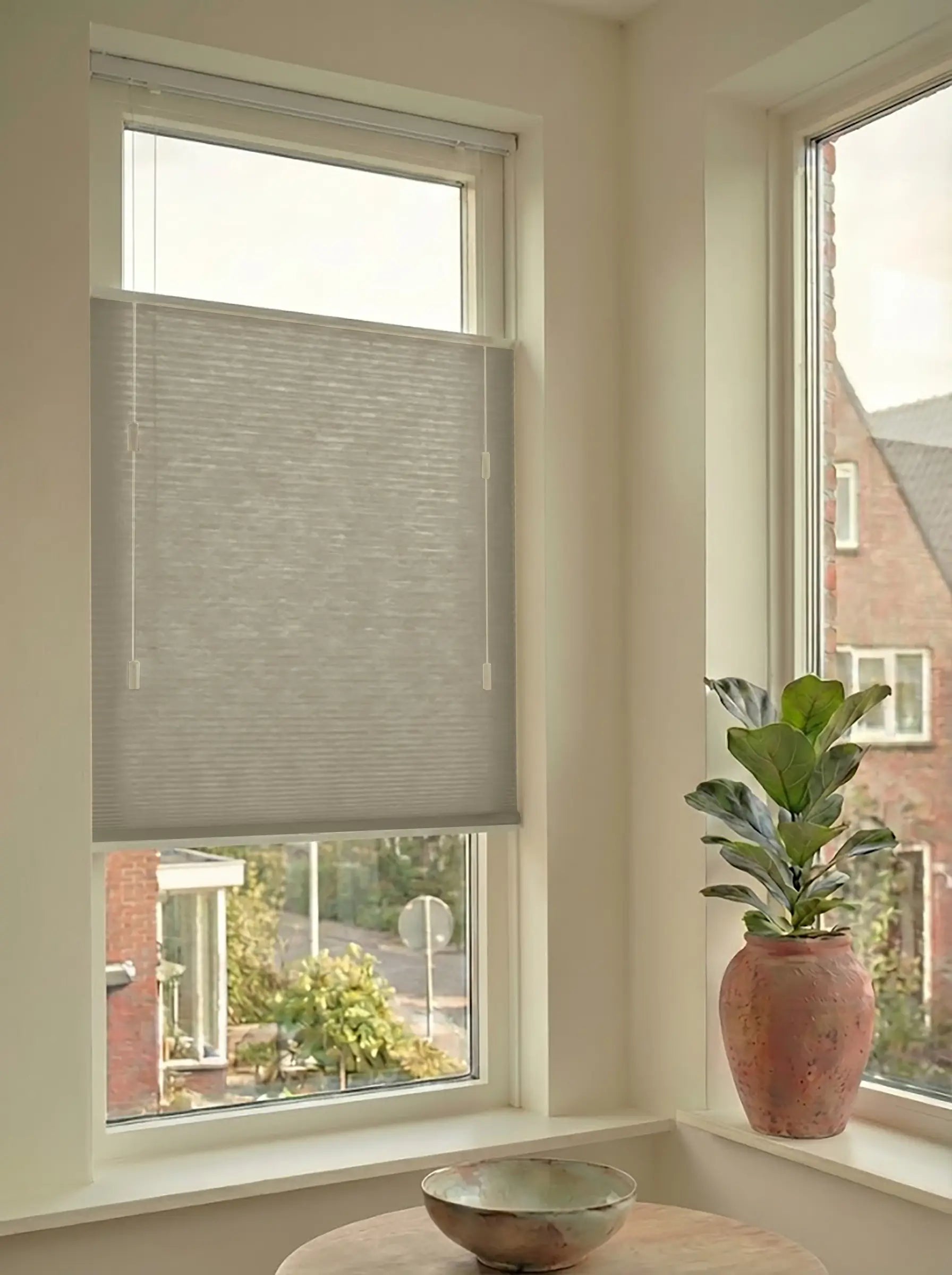 Lichtdoorlatend plisségordijn in Top Down Bottom Up uitvoering, gemonteerd in een licht interieur bij een raam met uitzicht.